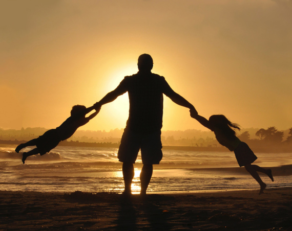 Père et enfants devant un coucher de soleil