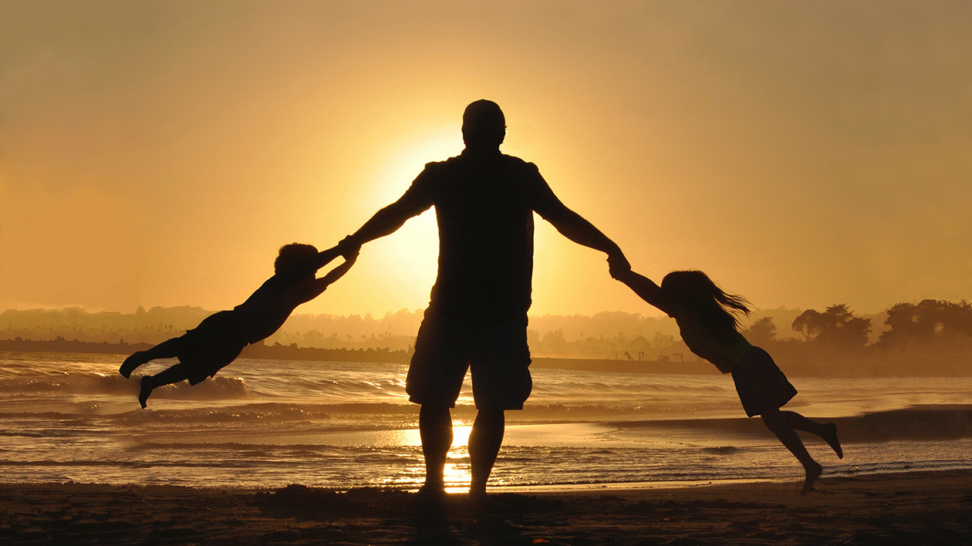 Père et enfants devant un coucher de soleil